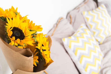 Beautiful yellow sunflowers bouquet with craft paper near bed in bedroomの写真素材