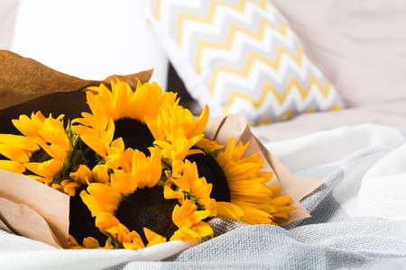 Beautiful authentic yellow sunflowers bouquet with craft paper in bedの写真素材