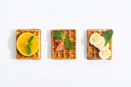 Belgium waffles with strawberry, banana and orange with syrup on whiteの写真素材