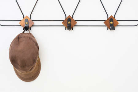 Empty hanger with black metal and wooden elements on white textured wall and capの写真素材