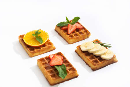 Belgium waffles with strawberry, banana and orange with syrup on whiteの写真素材