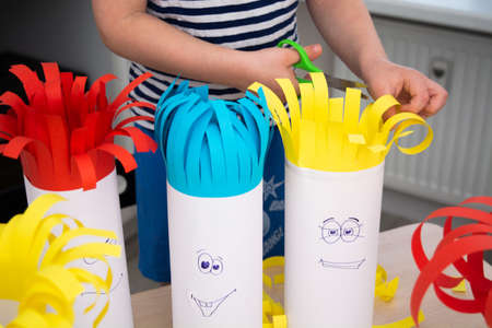Preschool boy cutting paper hair with scissors on handmade funny headsの写真素材