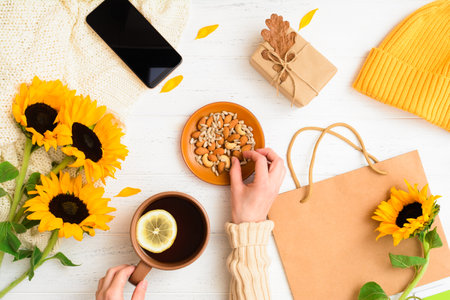 Autumn flat lay with female hands holding nut and cup of tea. Cozy homeの写真素材