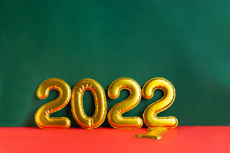 Golden numbers 2022 year inscription on green uneven surface and red backgroundの写真素材
