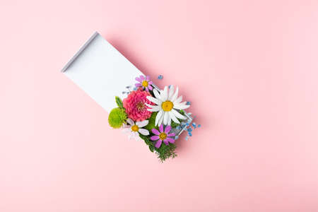 Stylish fresh flowers arrangement in white gift box on pink background