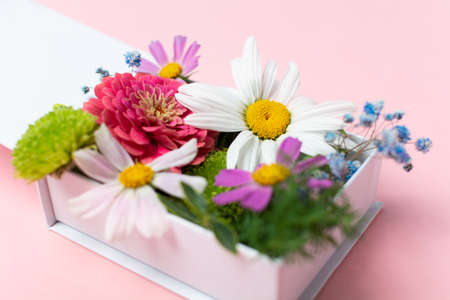Stylish fresh flowers arrangement in white gift box on pink backgroundの写真素材