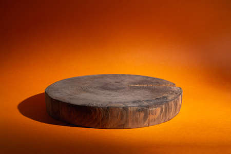 Empty showcase of wooden circle podium on orange backgroundの写真素材