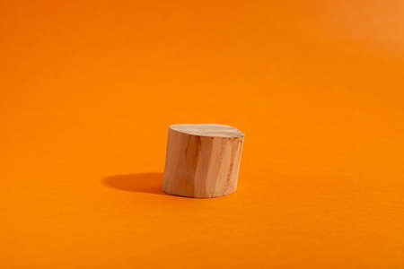 Empty showcase of wooden circle podium on orange. Scene with geometrical formの写真素材