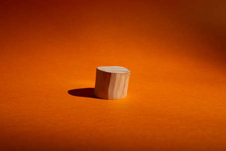 Empty showcase of wooden circle podium on orange. Scene with geometrical formの写真素材