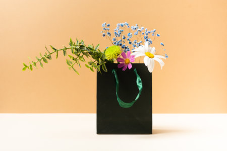 Paper bag with beautiful summer garden flowers and plants on beige backgroundの写真素材