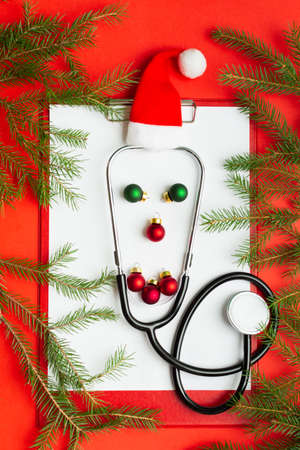 Medical Christmas concept with funny face of stethoscope and balls on clipboardの写真素材