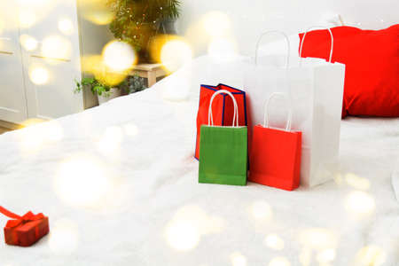 Christmas shopping concept with paper bags and gift box on bed at homeの写真素材