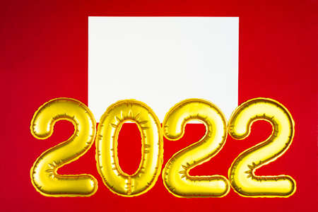 New Year 2022. Golden numbers with list of white paper on red with copy spaceの写真素材