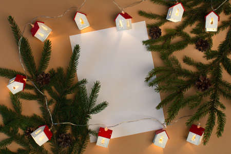 Blank white paper with fir tree and christmas lights on beige backgroundの写真素材