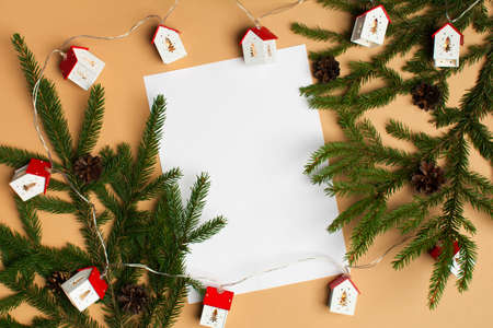 Blank white paper with fir tree and christmas lights on beige backgroundの写真素材