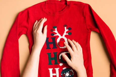 Funny Christmas sweater with female hands preparing clothes for New Yearの写真素材