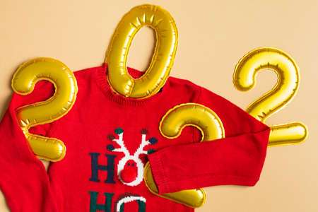 Funny Christmas sweater holding 2022 Year on beige background. Flat lay. Topの写真素材