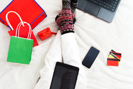 Christmas online shopping concept with internet, gift bags and cards on bedの写真素材
