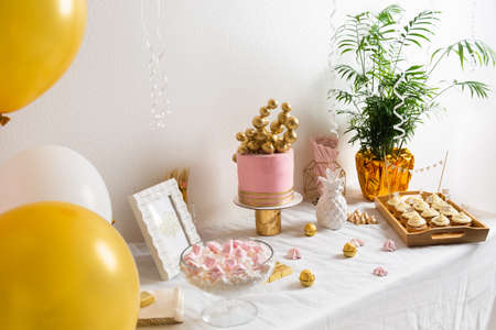 Holiday birthday table with cake and ballons. Pink and golden decorationの写真素材
