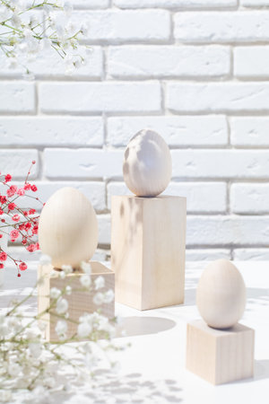 Easter postcard with three wooden eggs on podiums and flowers. Copy spaceの写真素材