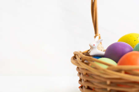 Colorful Easter eggs in wicker basket with ceramic bunny. Happy Easter concept