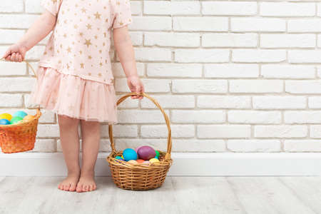 Unrecognizable girl with colorful Easter eggs in two wicker basketsの写真素材