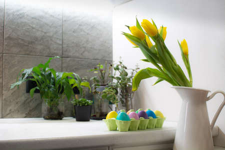 Many colorful Easter eggs in carton box on table in kitchen interiorの写真素材