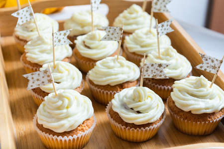 Tasty cupcakes with cream on wooden tray on holiday table with flagsの写真素材