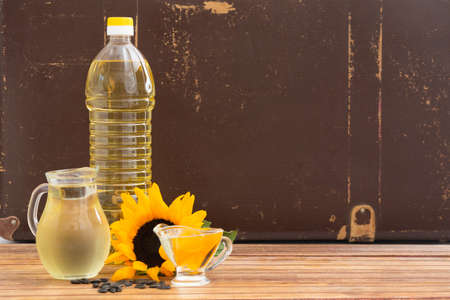 Plastic bottle and glass jars with sunflower oil on wooden tableの写真素材