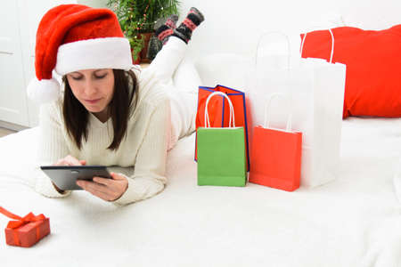 Beautiful smiling woman in Santa hat holding phone and bank plastic cardの写真素材
