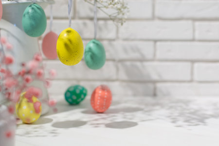 Closeup view of hanging fake eggs on table with brick wall with copy space. Decorated interiorの写真素材
