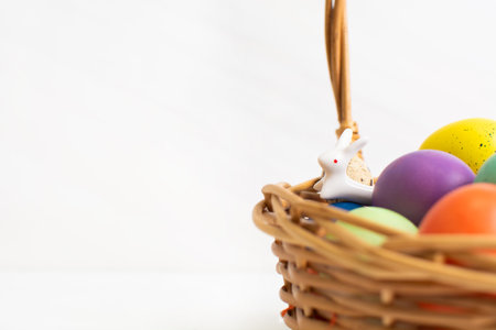 Wicker basket with bright colorful eggs and with text Happy Easter and flowerの写真素材