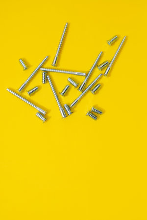 Steel screws for furniture different types on yellow background. Top viewの写真素材