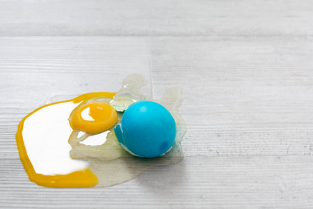 Closeup view of broken Easter blue egg with the leaked yolk on the floorの写真素材