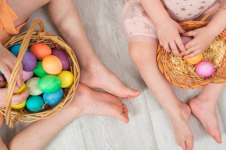 Unrecognizable children sitting on the floor with colorful Easter eggs in two wicker basketsの写真素材