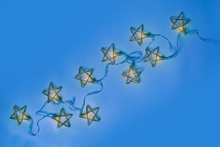 Golden metal garland with lights on blue background with copy spaceの写真素材