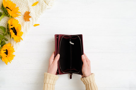 Woman hands holding open empty burgundy leather wallet on wooden tableの写真素材