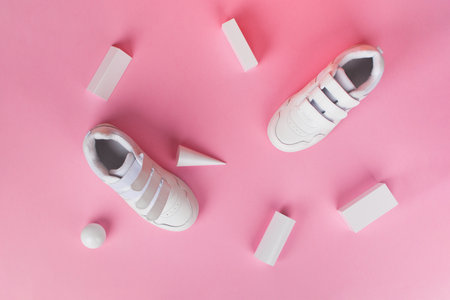 White children's sneakers on pink background. Minimal background. Fashion blog or magazine concept. Advertisement for sale or shop. Top view. Flat layの写真素材