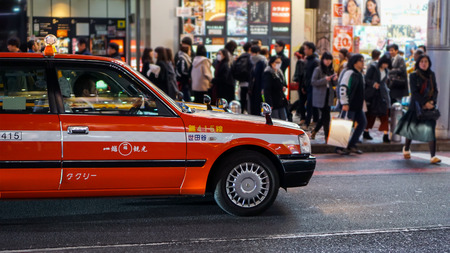 SHIBUYA, TOKYO / JAPAN - MARCH 02, 2018: A shiny orange taxi during rush hourのeditorial素材