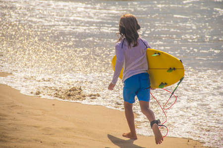 Surfer boy running to the shore of the beach with his surfboard