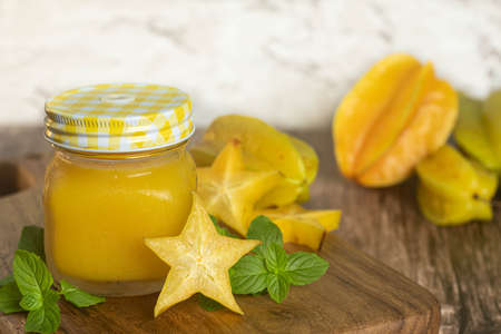 star fruit, carambola or carambola juice, accompanied by fresh fruits on a wooden table and on a marble background.の写真素材