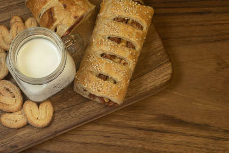 Hawaiian style filled puff pastry dessert, accompanied by a glass of milk on a wooden boardの写真素材