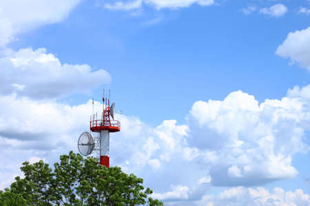 Air traffic control communications tower against cloudy blue sky, symbolic backgroundの写真素材