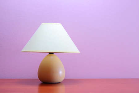 Lamp on a wooden table against purple wallの写真素材