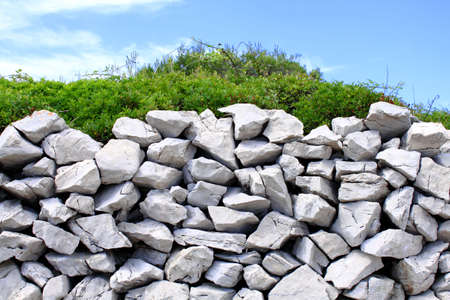 Traditional mediterranean stone wall with thick green bushの写真素材