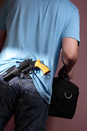 Man with handgun tucked in belt leaving room carrying black bag