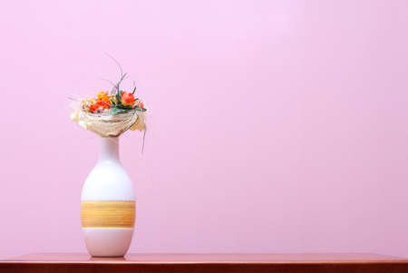 Ceramic vase with dry flowers on wooden table against purple wallの写真素材