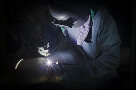 A man with personal protective equipment is doing welding in low light areaの写真素材