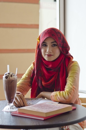 beautiful young muslim woman with lovely smiles having lunch at coffee shopの写真素材