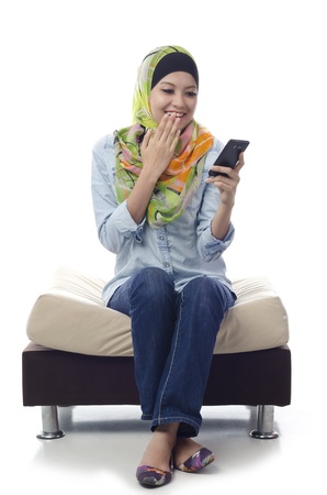 Beautiful muslim woman shocked and happy when got good news from somebody send message using phoneの写真素材